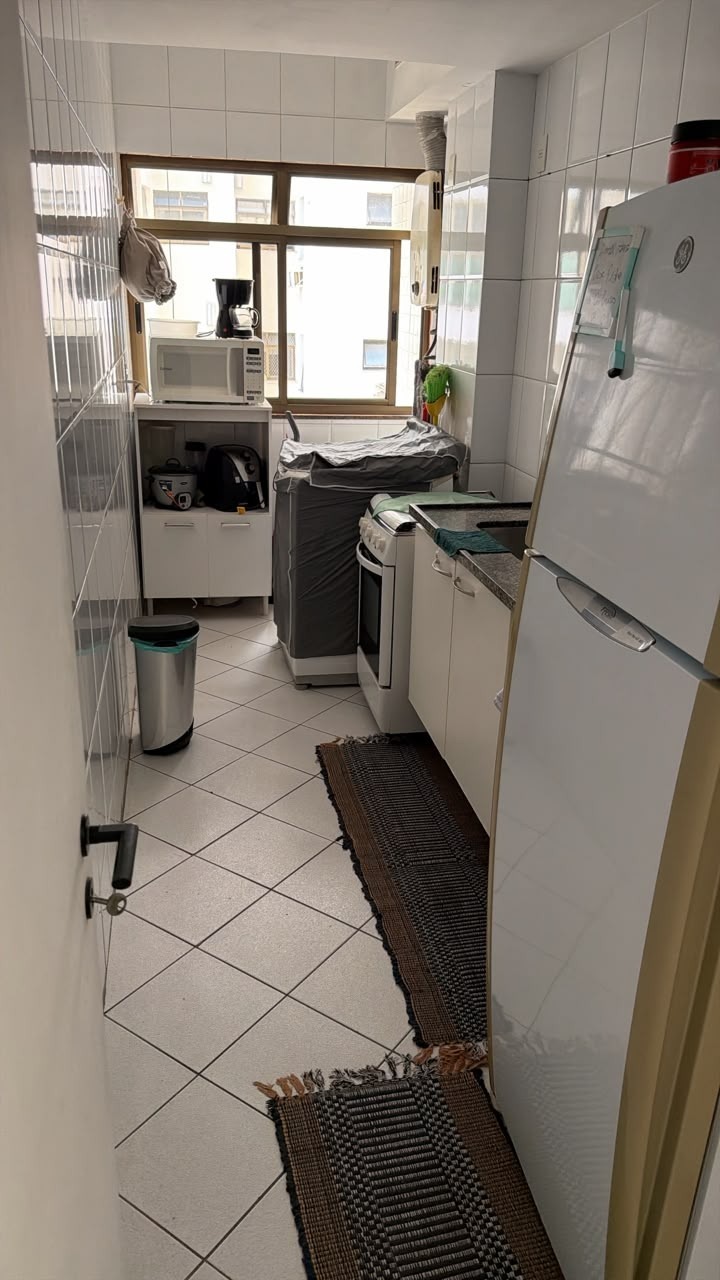 Cozinha do apartamento mobiliado na Rua Aroazes, com armários brancos, bancada de granito, fogão, geladeira e janela