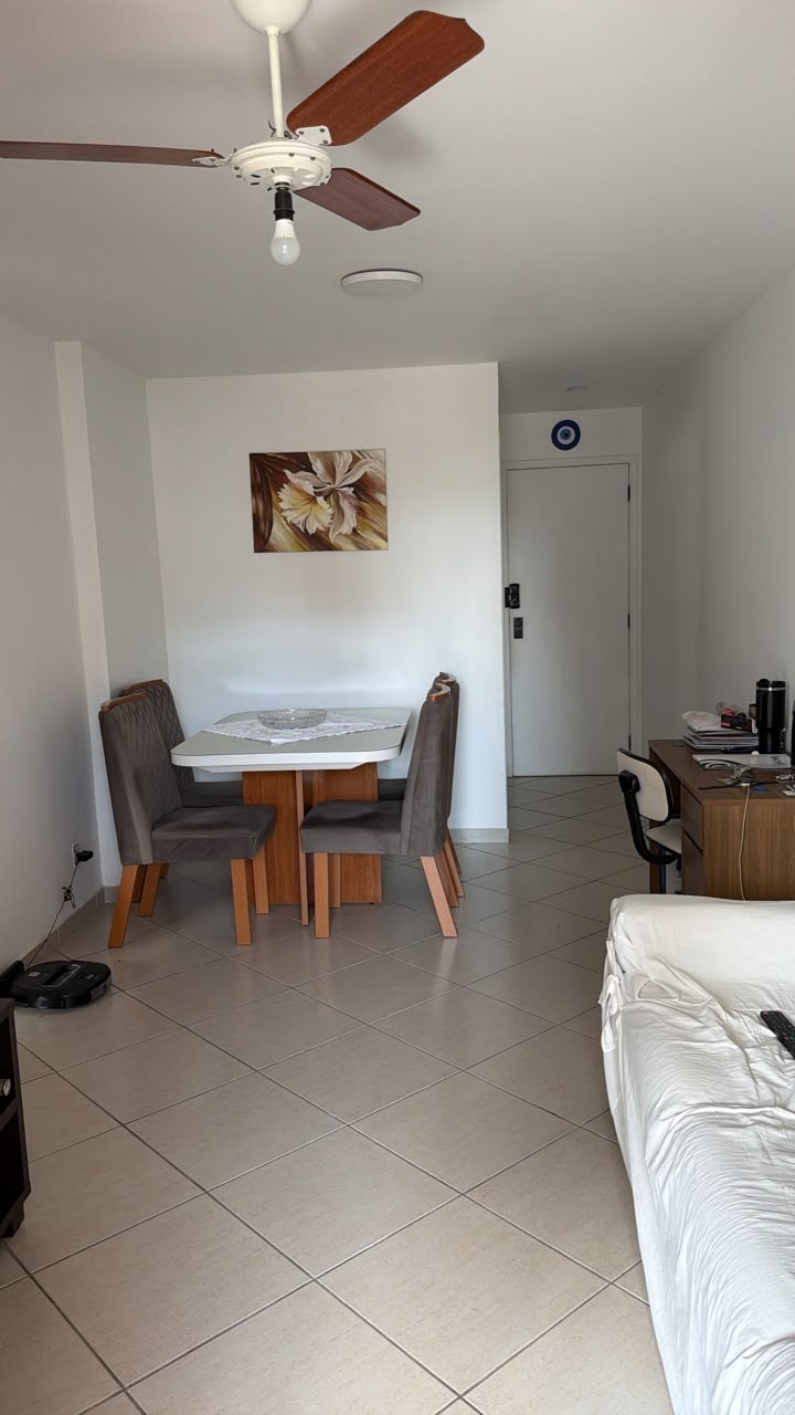 Sala de jantar do apartamento mobiliado na Rua Aroazes, com mesa de vidro, quatro cadeiras estofadas, ventilador de teto e porta de entrada ao fundo
