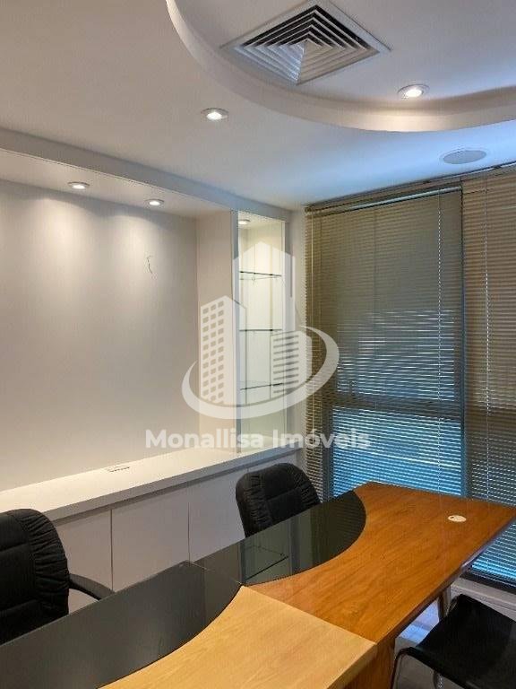 Área de reunião da sala comercial no Le Monde Office, com mesa de madeira, cadeiras pretas e persiana