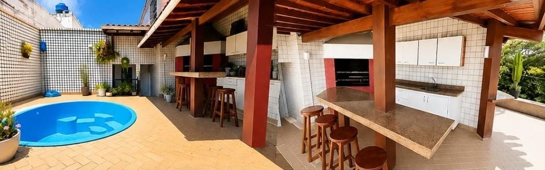 Piscina e área gourmet da cobertura linear no Jardim Oceânico, com piscina redonda, bancada de granito, banquetas e churrasqueira