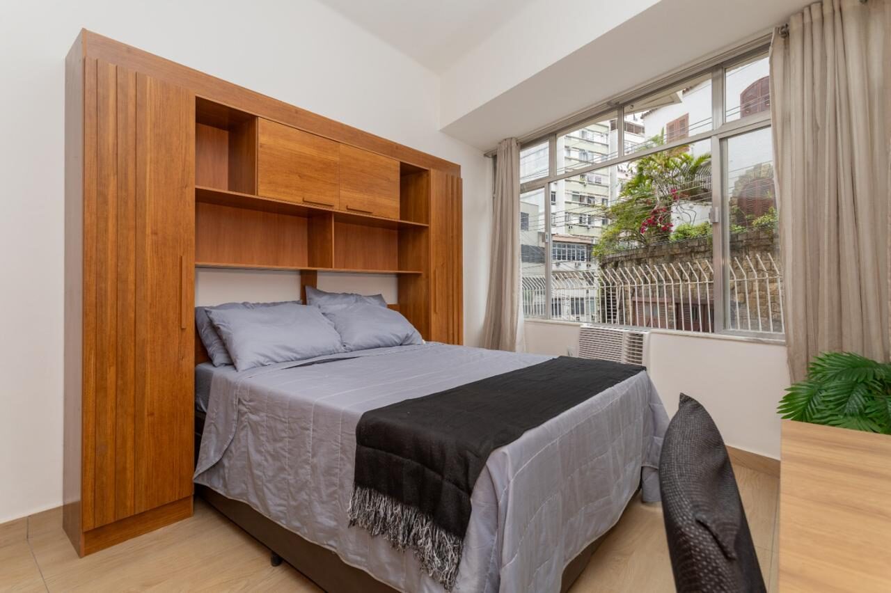 Cama do estúdio em Copacabana ao lado da janela, com armário de madeira embutido