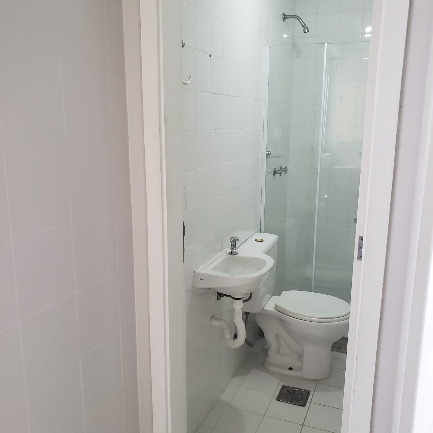 Banheiro do estúdio em Copacabana, com vaso sanitário branco, box de vidro com ducha e bancada de granito