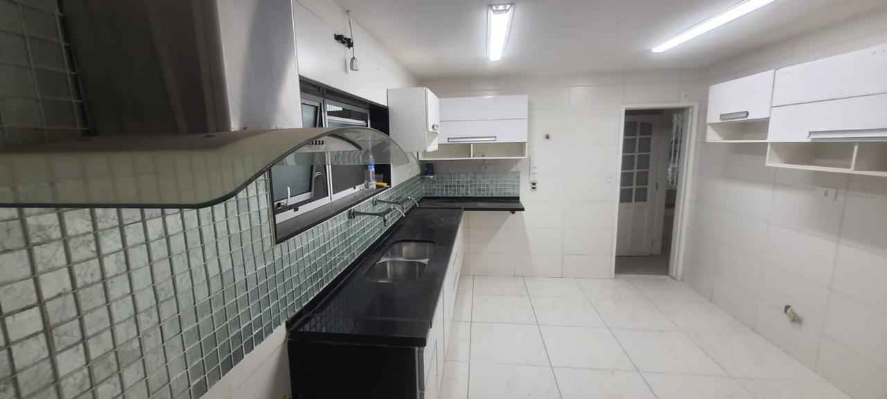 Cozinha do apartamento para locação em Ipanema, com bancada de granito preto, cuba dupla de inox, azulejos verdes e armários brancos