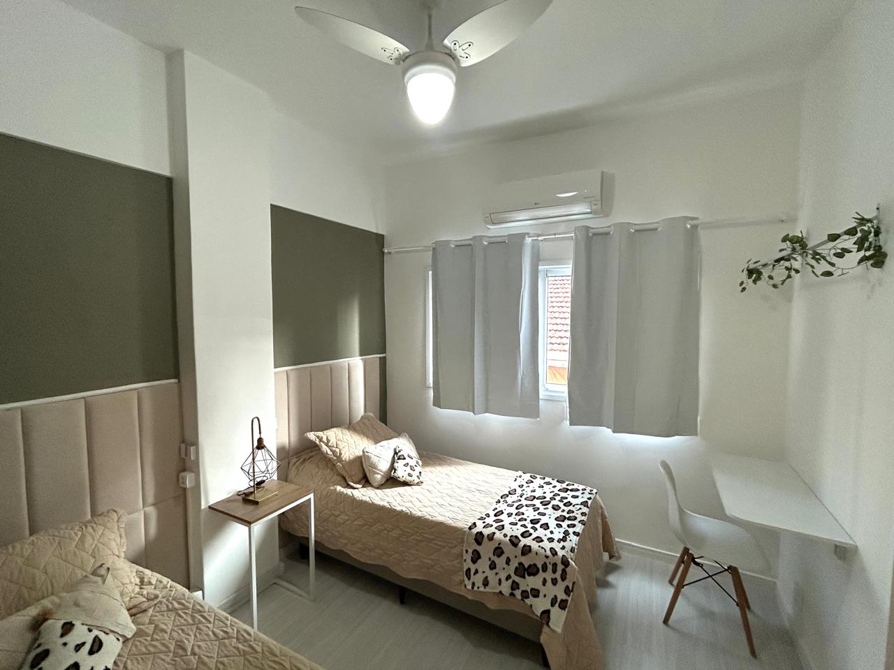 Segundo quarto do apartamento em Ipanema, com cabeceira estofada, escrivaninha e ar-condicionado