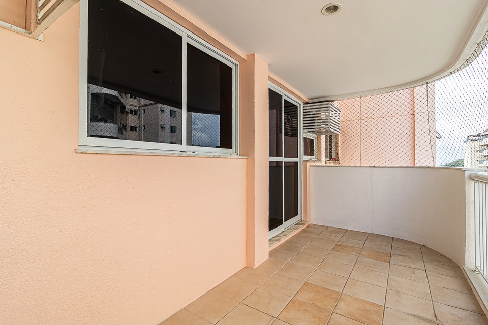 Varanda do apartamento no Condomínio Pablo Picasso, no Recreio dos Bandeirantes, Barra Bonita, com piso cerâmico, parede rosada, janelas grandes e tela de proteção