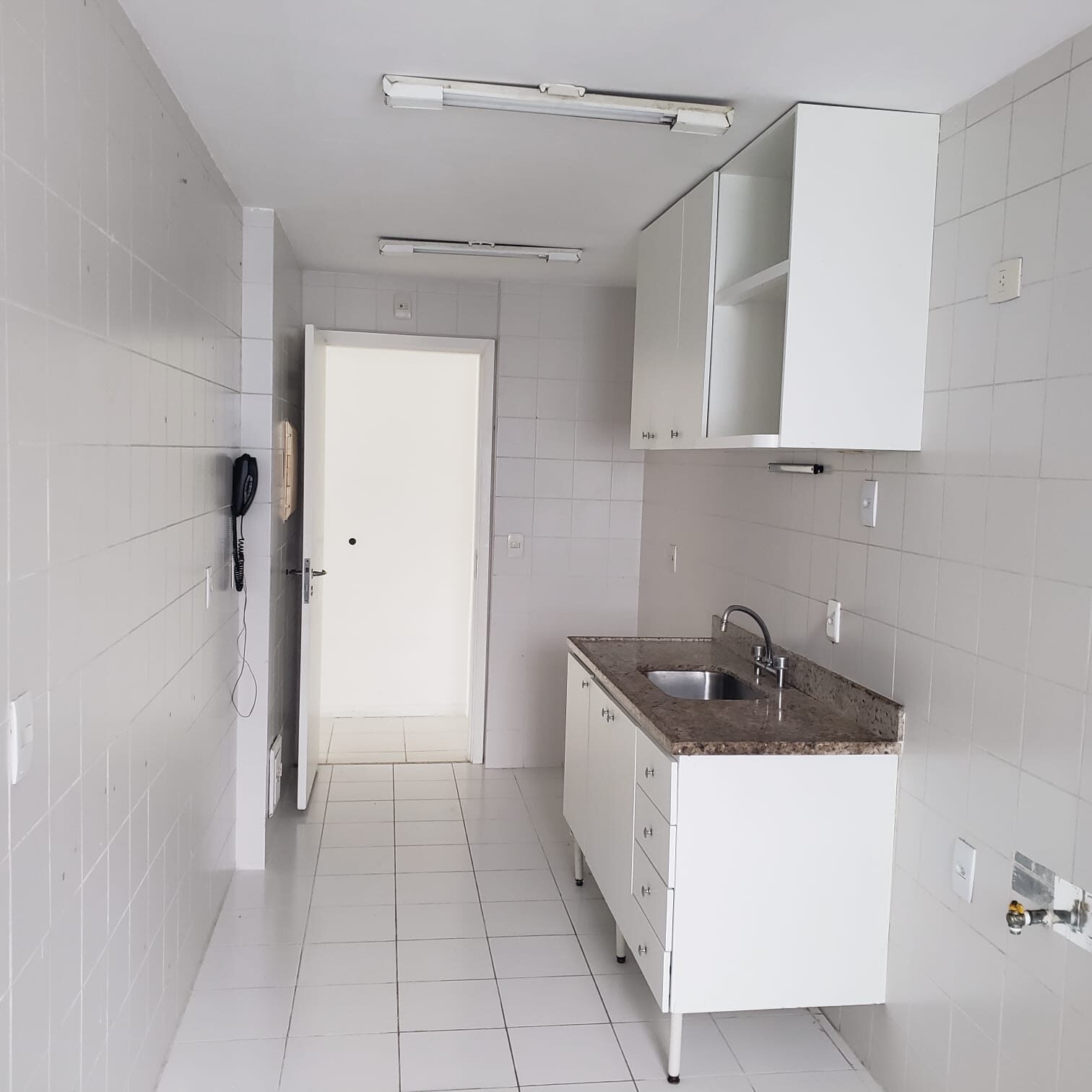 Cozinha do apartamento na Vila do Pan, com armários brancos, bancada de granito e pia de inox