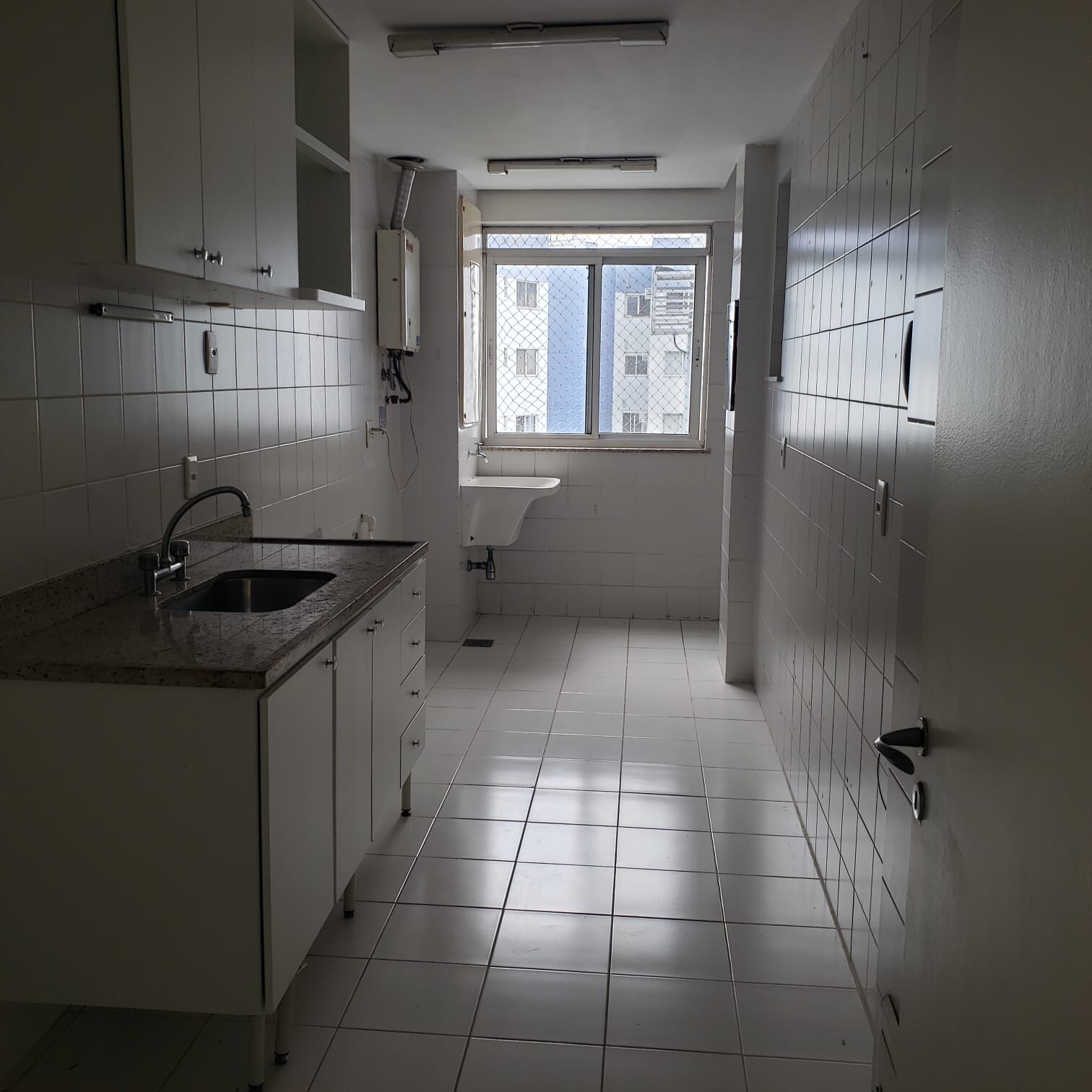 Cozinha do apartamento na Vila do Pan com a área de serviço, tanque e janela ao fundo